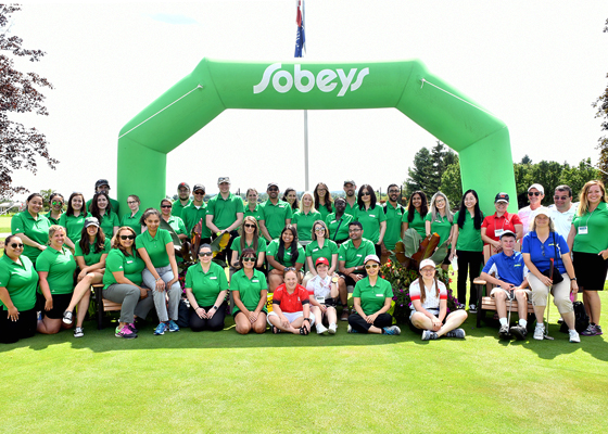 A group of FreshCo employees packing food into milk crates.